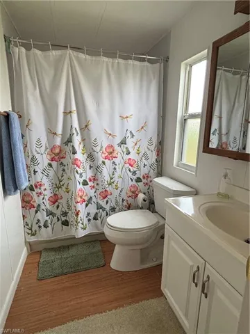 Full bathroom featuring vanity, a shower tub combo, toilet and wood finished floors