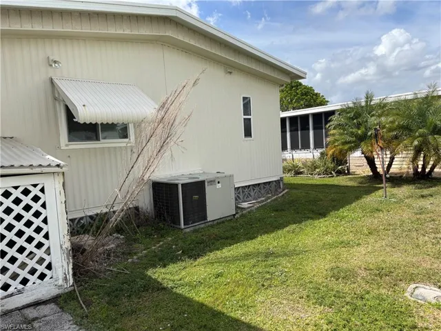 View of side of home with a yard, central AC