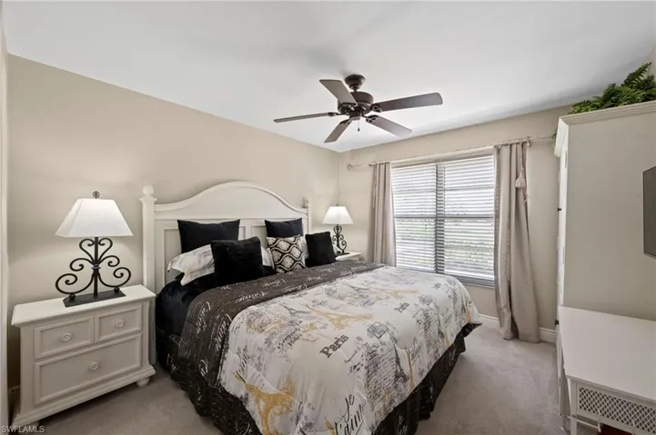 Bedroom with light colored carpet, baseboards, and a ceiling fan