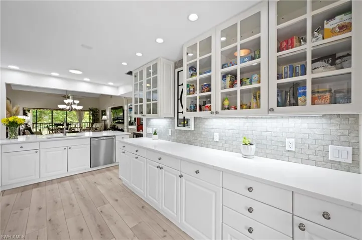 Kitchen with stainless steel dishwasher, glass insert cabinets, white cabinets, tasteful backsplash, and recessed lighting