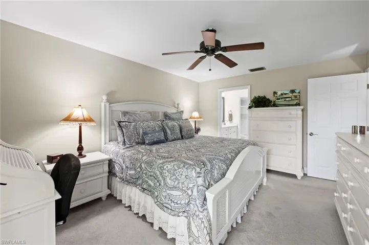 Bedroom featuring light colored carpet, ensuite bath, and ceiling fan