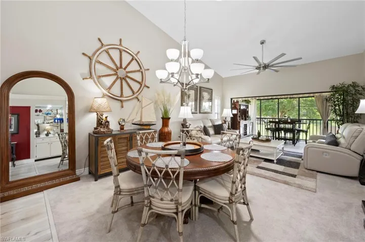 Dining area featuring high vaulted ceiling, ceiling fan, arched walkways, light colored carpet, and a chandelier