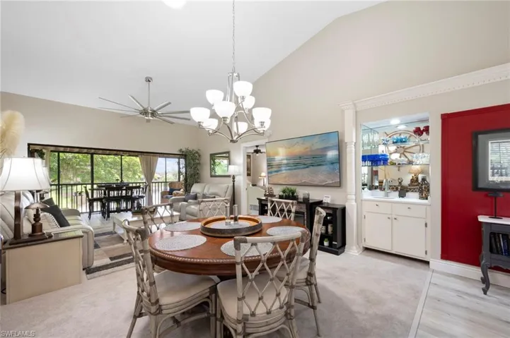 Dining area featuring high vaulted ceiling, a ceiling fan, light wood-type flooring, and a chandelier