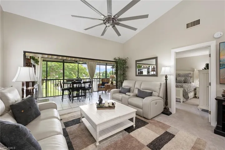 Living area featuring high vaulted ceiling, a ceiling fan, and light carpet