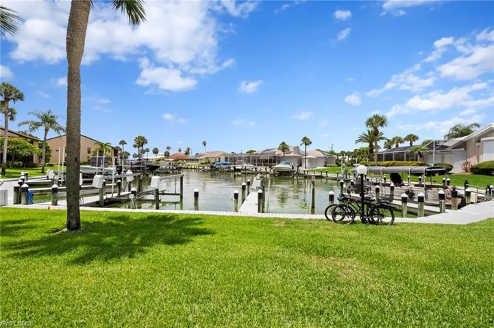 Dock area featuring a residential view, boat lift, a water view, and a lawn