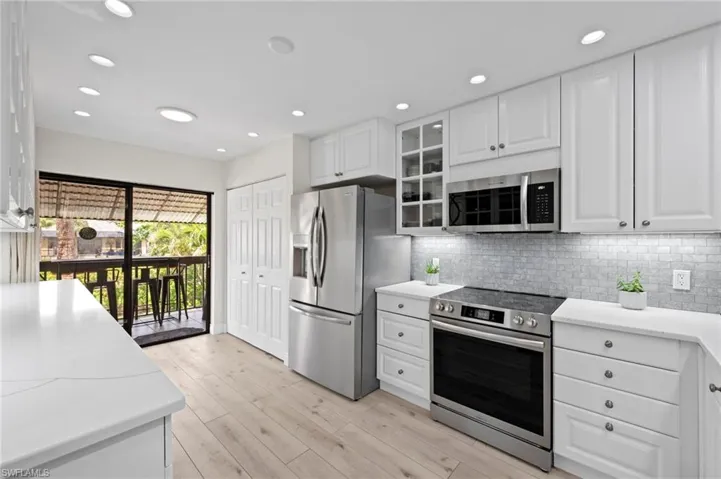 Kitchen featuring stainless steel appliances, white cabinets, decorative backsplash, light countertops, and recessed lighting