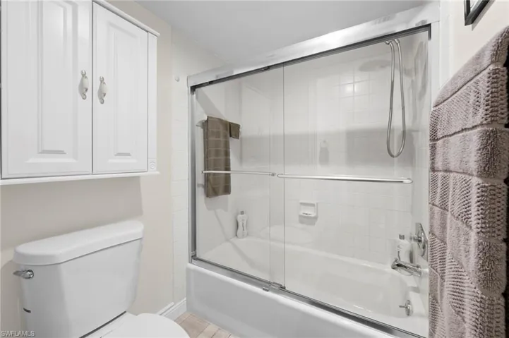 Full bathroom with combined bath / shower with glass door and toilet