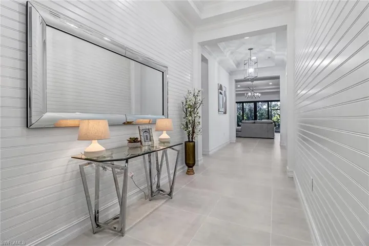 Corridor with hanging lights, crown molding, wood walls, and light tile patterned floors