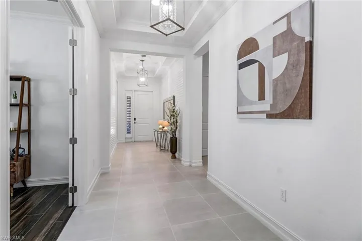 Hall featuring hanging lights, a tray ceiling, and crown molding