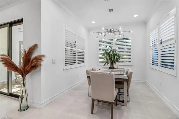 Dining space with crown molding, suspended lighting, and light tile patterned floors