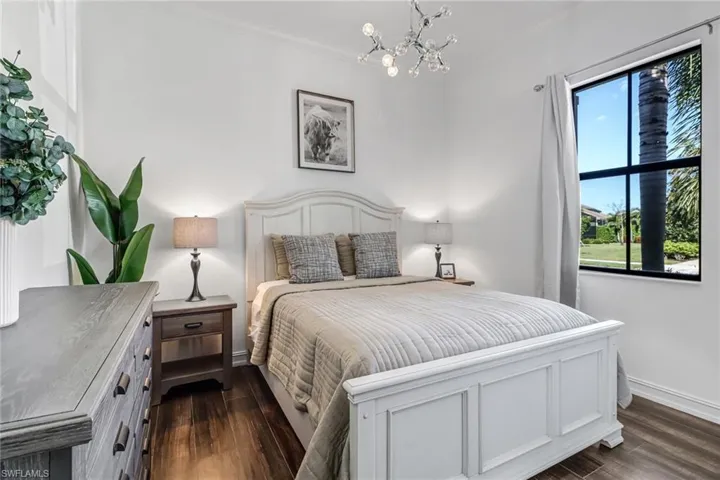 Bedroom with dark wood finished floors, suspended lighting, and ornamental molding