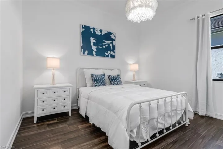 Bedroom with dark wood-style flooring, ornamental molding, and hanging lights