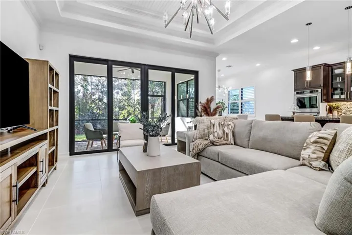 Living room with hanging lights, light tile patterned floors, and ornamental molding