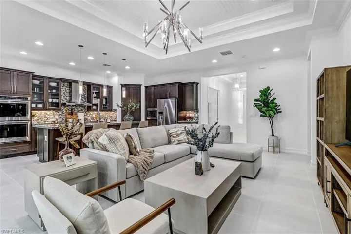 Living room featuring hanging lights, ornamental molding, a raised ceiling, and light tile patterned floors