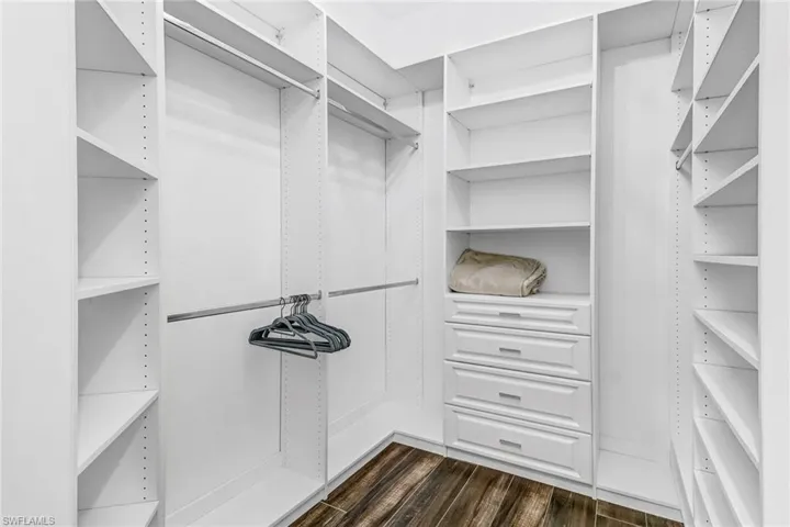 Walk in closet with dark wood-style floors