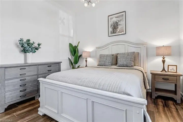Bedroom featuring dark wood finished floors, a chandelier, and crown molding