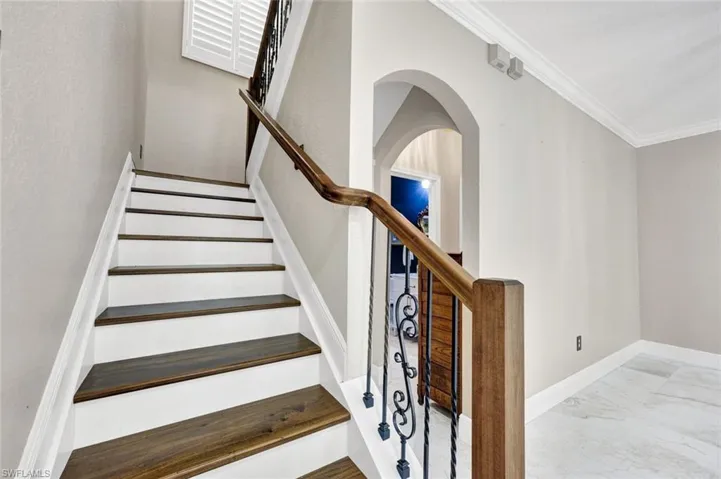 New and updated staircase with wood-finish treads, white risers, and a wrought iron railing with a wood-finish handrail