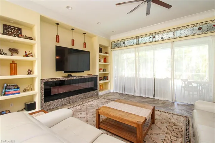 Living room with a healthy amount of sunlight, built in shelves, and crown molding