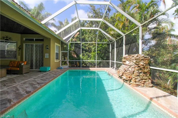 View of swimming pool featuring glass enclosure and a patio area