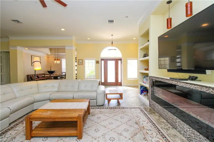 Carpeted living room featuring built in features, ceiling fan, and crown molding