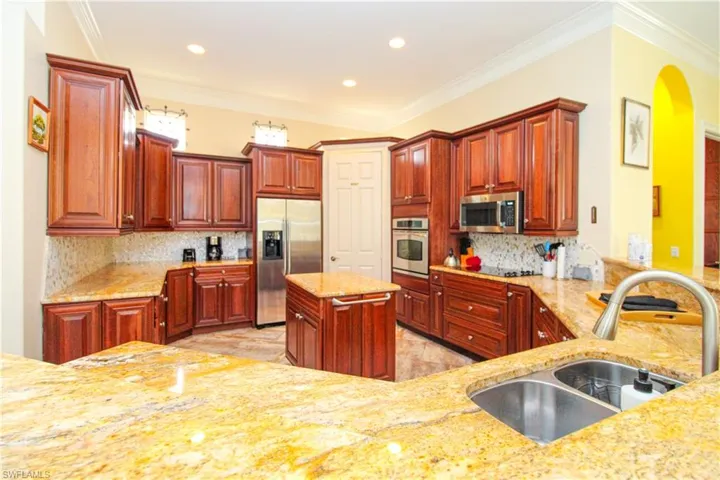 Kitchen featuring crown molding, backsplash, appliances with stainless steel finishes, sink, and a center island