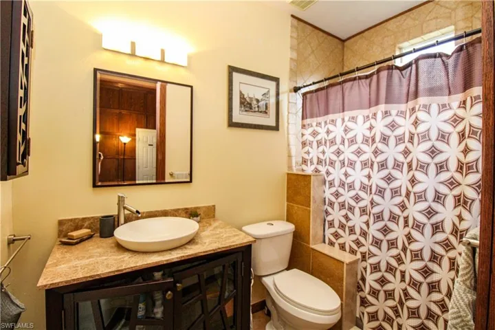 Bathroom with toilet, vanity, and curtained shower