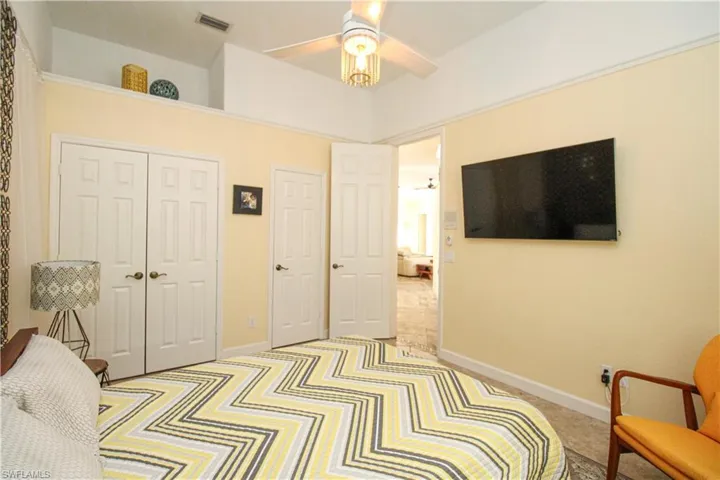 Carpeted bedroom with ceiling fan and a closet
