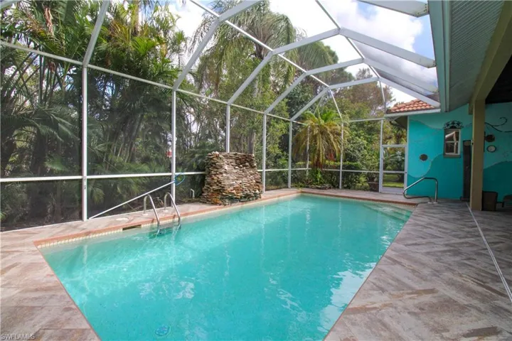 View of swimming pool featuring glass enclosure and a patio area