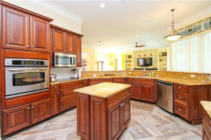 Kitchen with sink, ceiling fan, crown molding, pendant lighting, and appliances with stainless steel finishes