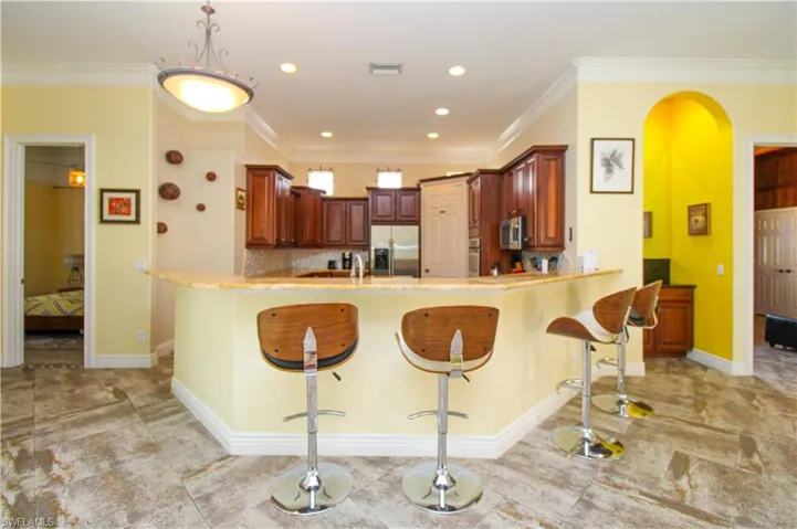Kitchen featuring tasteful backsplash, ornamental molding, stainless steel appliances, a kitchen breakfast bar, and kitchen peninsula