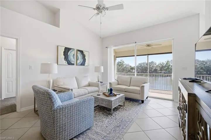 Living area featuring light tile patterned floors, a ceiling fan, and high vaulted ceiling with lake view