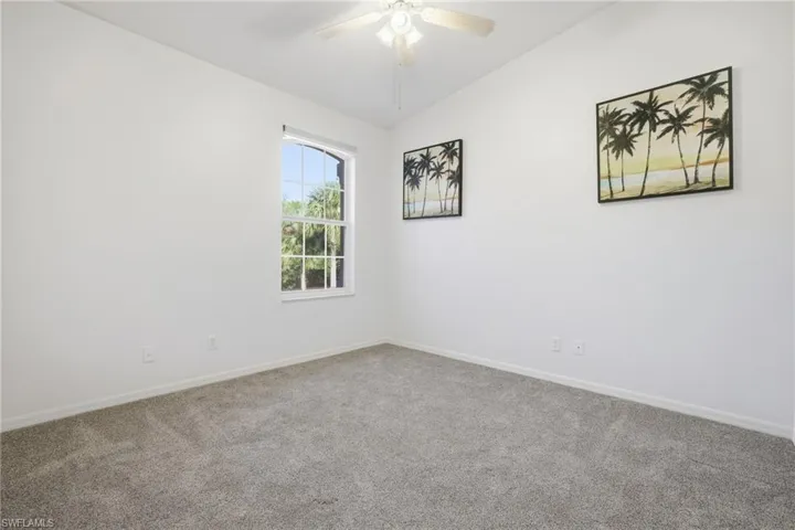 Guest bedroom featuring vaulted ceiling, carpet floors, and a ceiling fa