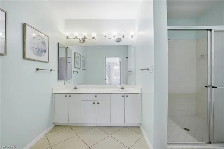 Primary Bathroom with a stall shower, double vanity, and light tile patterned floors