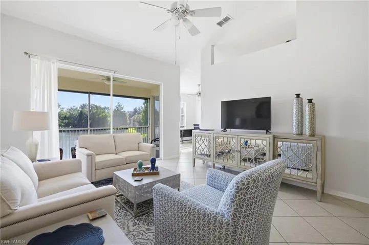 Living area featuring light tile patterned floors, a ceiling fan, and high vaulted ceiling with lake view