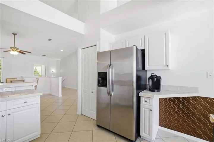 Kitchen featuring stainless steel fridge with ice dispenser, white cabinets