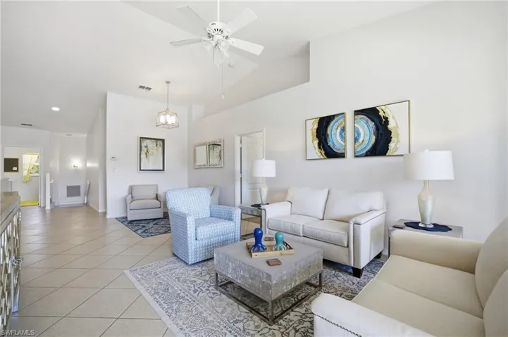 Living area featuring light tile patterned floors, a ceiling fan, and high vaulted ceiling with lake view