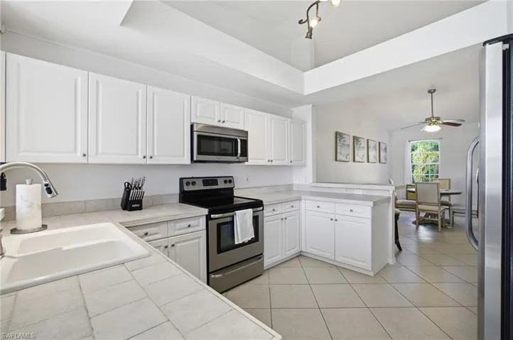 Kitchen featuring stainless steel appliances, white cabinets, tile countertops