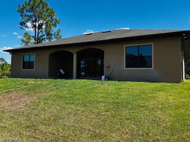 Back of property with stucco siding, a patio area, and a lawn