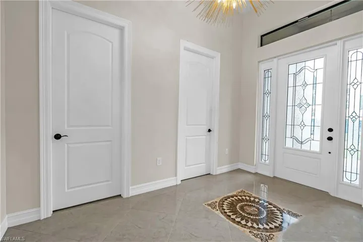 Entryway featuring a decorative inlaid floor medallion, large format tile flooring, and a transom window above the main entry