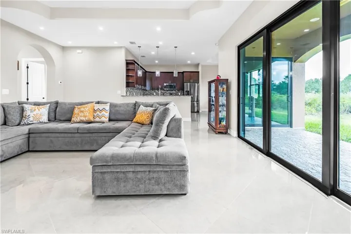 Spacious interior featuring large format light-toned tile flooring and expansive sliding glass doors