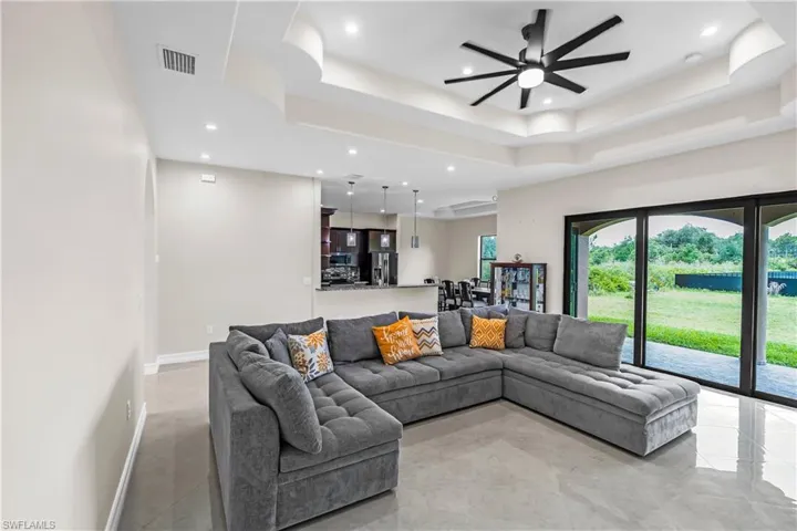 Spacious living area featuring coffered ceilings, recessed lighting, and large format tile flooring
