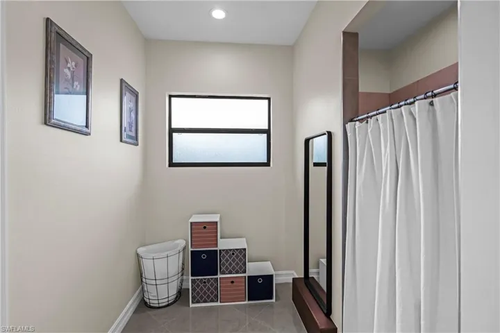 Bathroom featuring a frosted window with dark trim, recessed ceiling lighting, and tile flooring