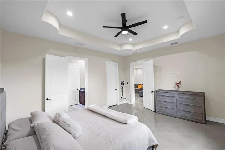Recessed lighting and a contemporary black ceiling fan complement the tray ceiling