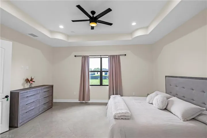 Spacious room featuring a tray ceiling with recessed lighting and a ceiling fan