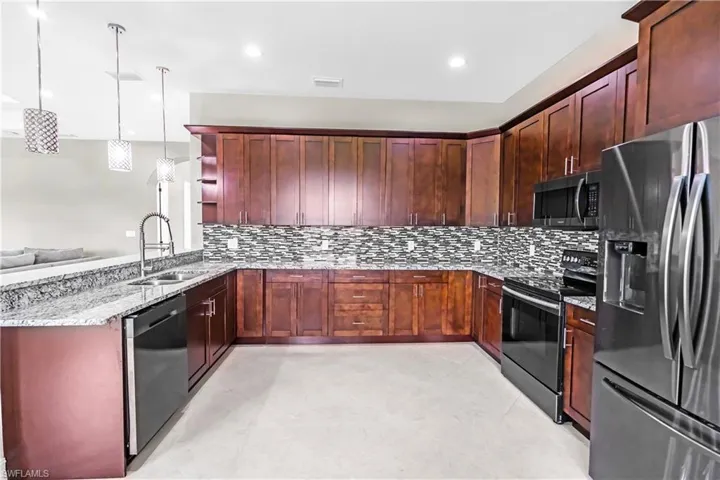 Kitchen featuring dark wood cabinetry, granite countertops, and a mosaic tile backsplash