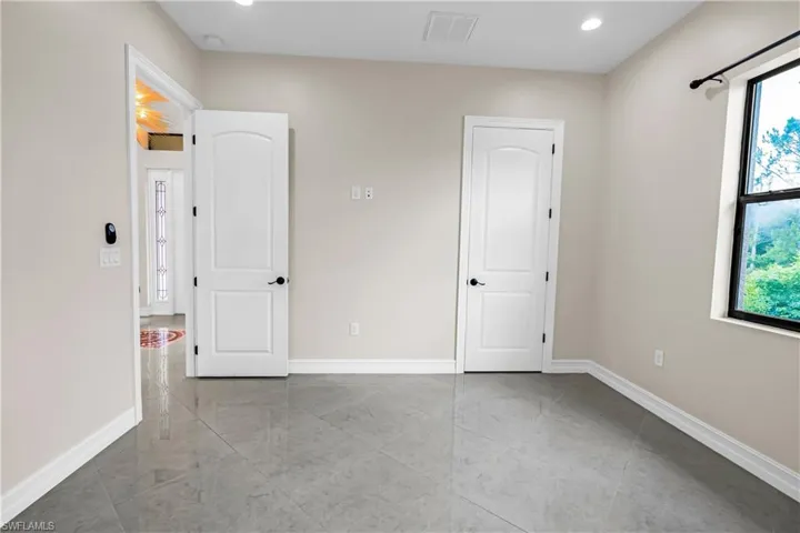 Room featuring light-toned walls, high ceilings with recessed lighting, and a window providing natural light