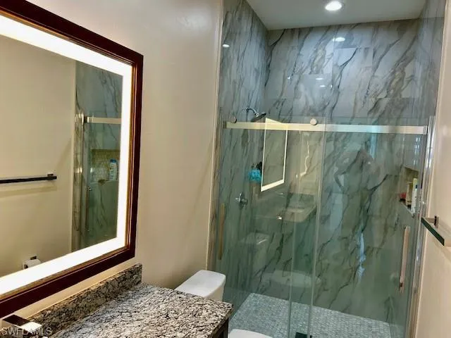 Full bathroom featuring vanity and a marble finish shower