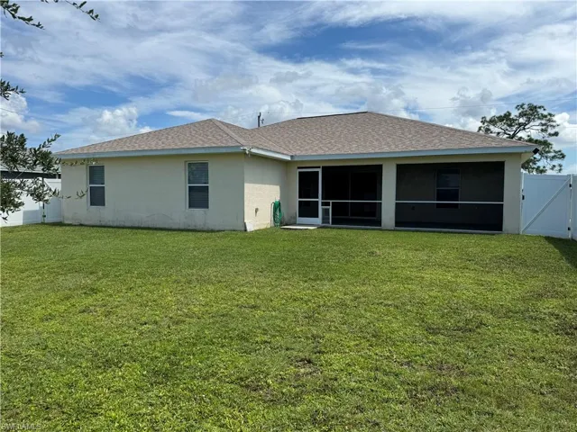 Back of house featuring a lawn and a sunroom