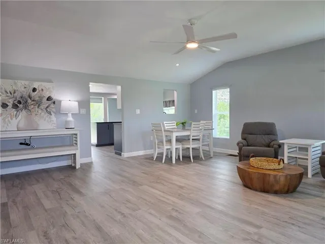 Dining space with healthy amount of natural light, wood finished floors, a ceiling fan, and lofted ceiling