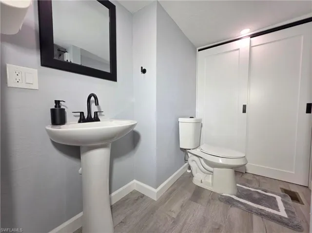 Half bathroom featuring wood finished floors and baseboards